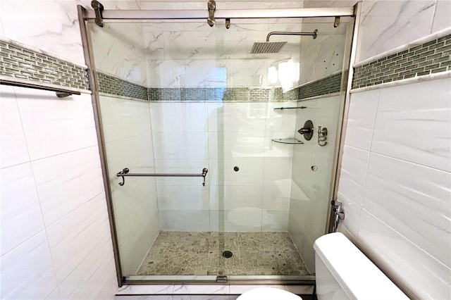 bathroom featuring tile walls, an enclosed shower, and toilet