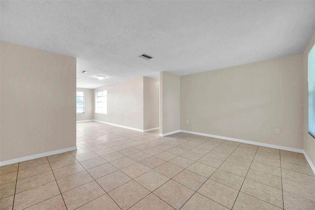 spare room featuring light tile patterned flooring and a textured ceiling