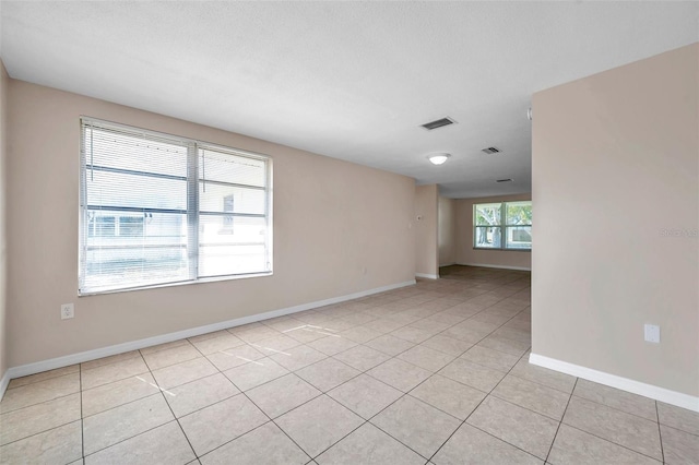 tiled empty room featuring a textured ceiling