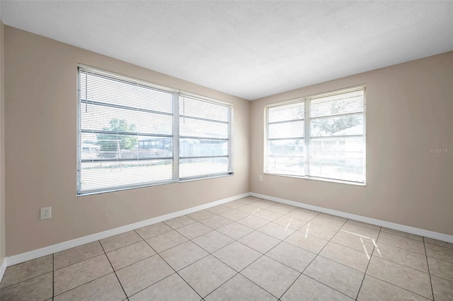 unfurnished room featuring a textured ceiling, a healthy amount of sunlight, and light tile patterned flooring