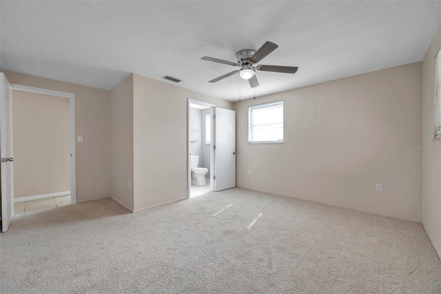 unfurnished bedroom featuring ceiling fan, light colored carpet, connected bathroom, and a textured ceiling