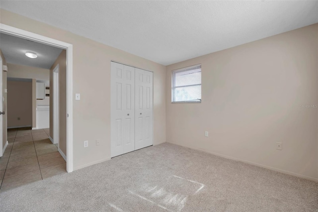 unfurnished bedroom featuring a closet, light carpet, and a textured ceiling