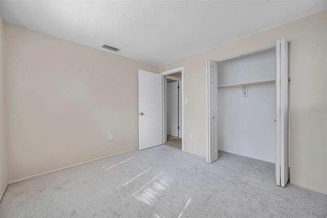 unfurnished bedroom with a closet, light carpet, and a textured ceiling