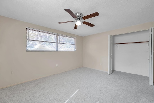 unfurnished bedroom featuring ceiling fan, light colored carpet, a closet, and a textured ceiling