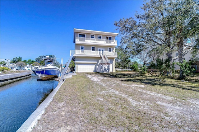 view of front of home featuring a garage, a water view, and a balcony