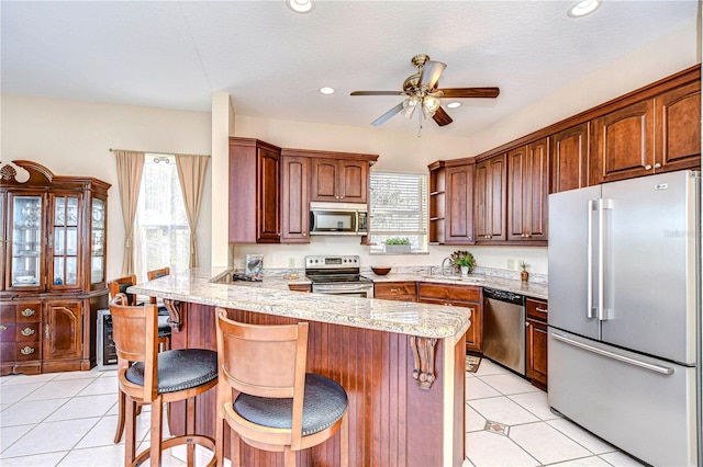 6801 Nowiki Ave, Hudson, FL 34667 - kitchen featuring stainless steel appliances, a peninsula, a ceiling fan, a breakfast bar, and light tile patterned floors