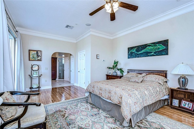 6801 Nowiki Ave, Hudson, FL 34667 - bedroom featuring wood finished floors, visible vents, arched walkways, crown molding, and baseboards