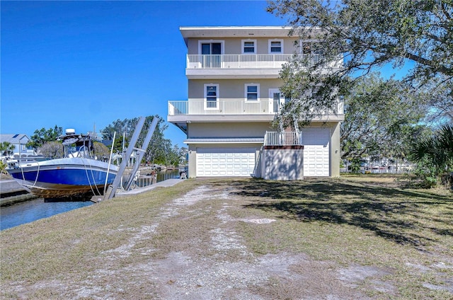 6801 Nowiki Ave, Hudson, FL 34667 - view of front of house with a balcony, stucco siding, driveway, boat lift, and a garage