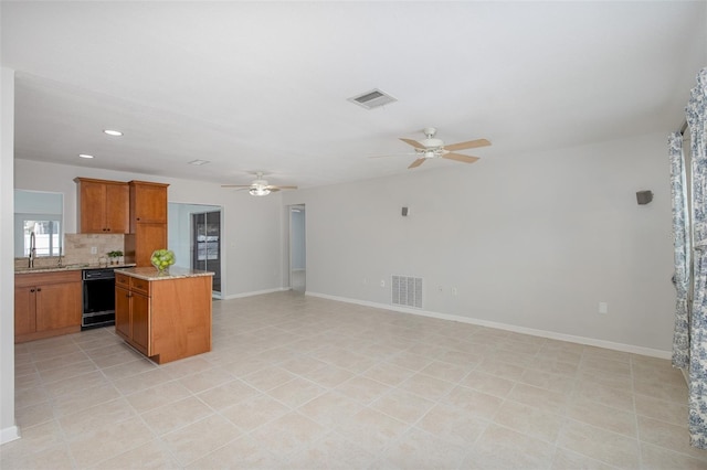 kitchen with light tile patterned floors, ceiling fan, dishwasher, tasteful backsplash, and a kitchen island