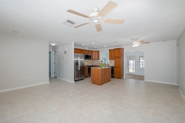 kitchen with light tile patterned flooring, a center island, appliances with stainless steel finishes, ceiling fan, and decorative backsplash