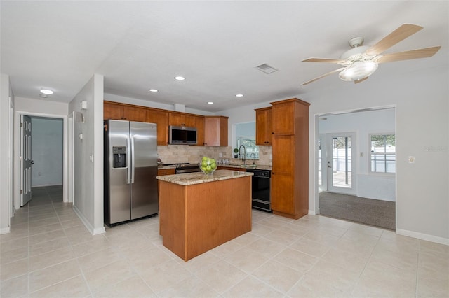 kitchen with sink, appliances with stainless steel finishes, backsplash, a center island, and light stone countertops