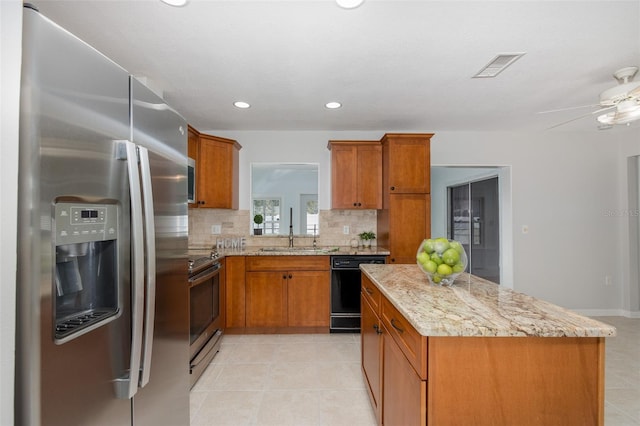 kitchen featuring sink, tasteful backsplash, light stone counters, a kitchen island, and stainless steel appliances