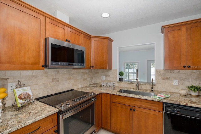 kitchen with light stone counters, stainless steel appliances, sink, and tasteful backsplash