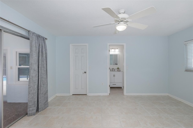 unfurnished bedroom featuring ensuite bathroom, sink, light tile patterned floors, and ceiling fan