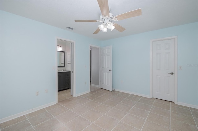 unfurnished bedroom featuring ensuite bathroom, ceiling fan, and light tile patterned flooring