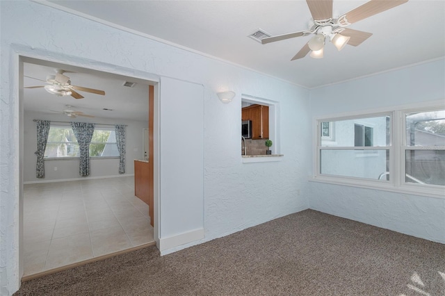 spare room with crown molding, ceiling fan, and carpet flooring