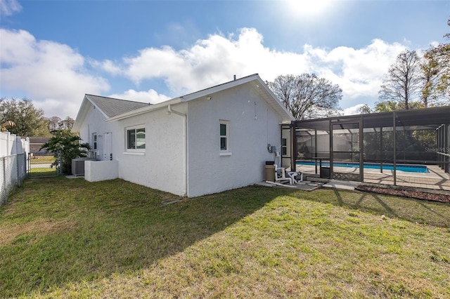 back of house featuring a fenced in pool, a yard, and glass enclosure