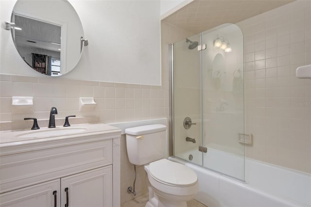 full bathroom featuring tile walls, vanity, shower / bath combination with glass door, and toilet