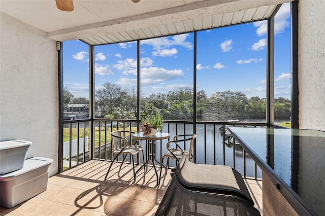 sunroom featuring a water view and ceiling fan