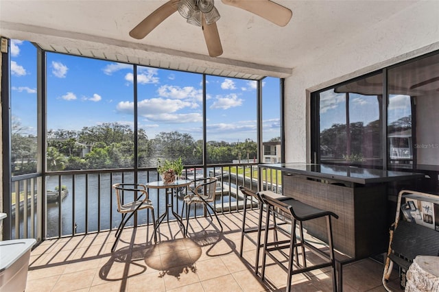 sunroom / solarium with a water view and ceiling fan