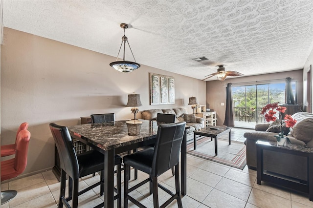 tiled dining area featuring a textured ceiling and ceiling fan