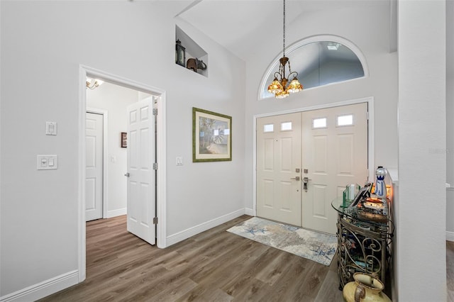 entrance foyer featuring high vaulted ceiling, a notable chandelier, and dark hardwood / wood-style flooring