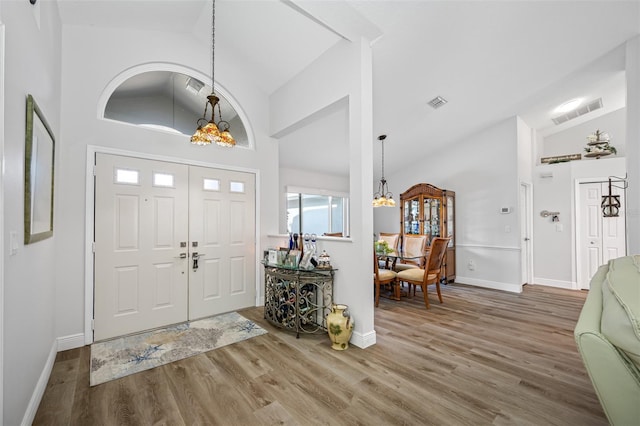 foyer with hardwood / wood-style flooring, a chandelier, and high vaulted ceiling