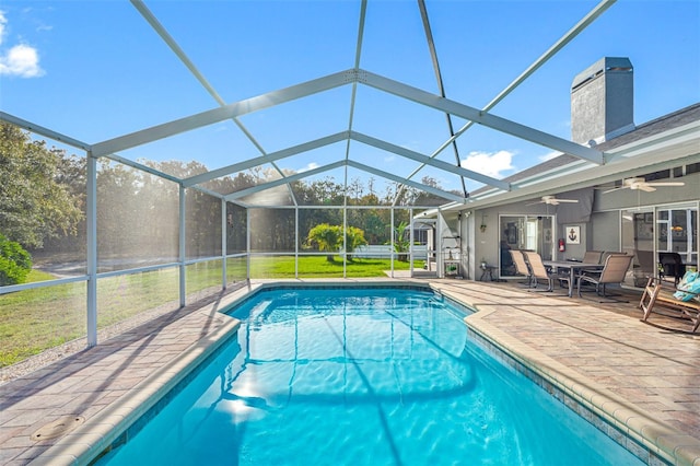 view of pool featuring ceiling fan, a patio, glass enclosure, and a lawn