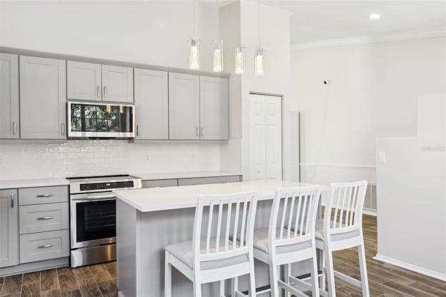 kitchen featuring gray cabinets, crown molding, appliances with stainless steel finishes, and pendant lighting