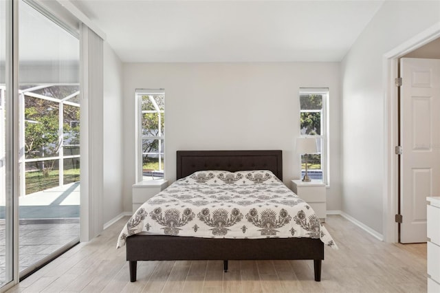 bedroom with access to exterior, light hardwood / wood-style floors, and multiple windows