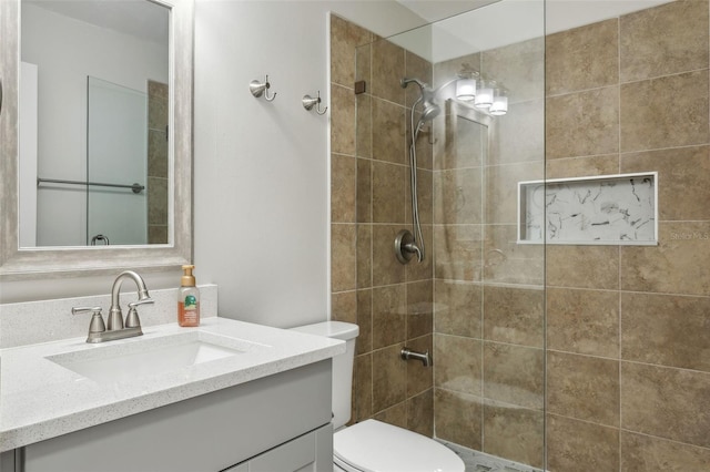 bathroom with vanity, toilet, and tiled shower