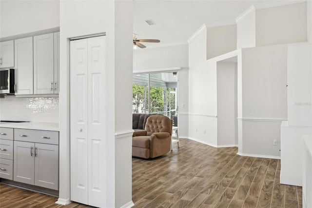 kitchen with gray cabinets, tasteful backsplash, crown molding, and dark hardwood / wood-style flooring