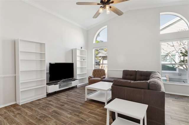 living room with dark wood-type flooring, ceiling fan, crown molding, and high vaulted ceiling