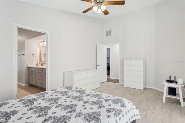 bedroom featuring ceiling fan, ensuite bath, vaulted ceiling, and light wood-type flooring