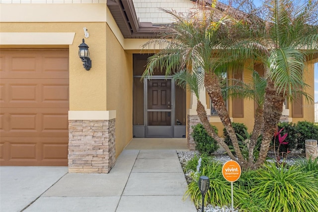 entrance to property featuring stone siding, an attached garage, and stucco siding