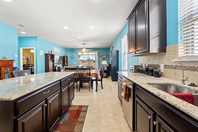 kitchen featuring visible vents, backsplash, stainless steel dishwasher, a ceiling fan, and a sink