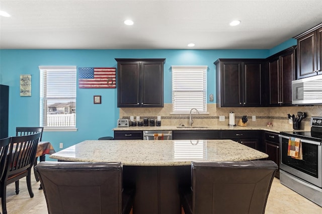 kitchen with tasteful backsplash, appliances with stainless steel finishes, a sink, and a center island