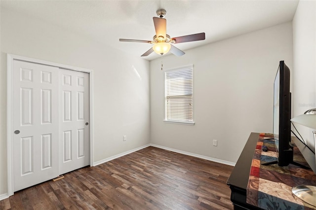 unfurnished bedroom with a ceiling fan, dark wood-style flooring, a closet, and baseboards