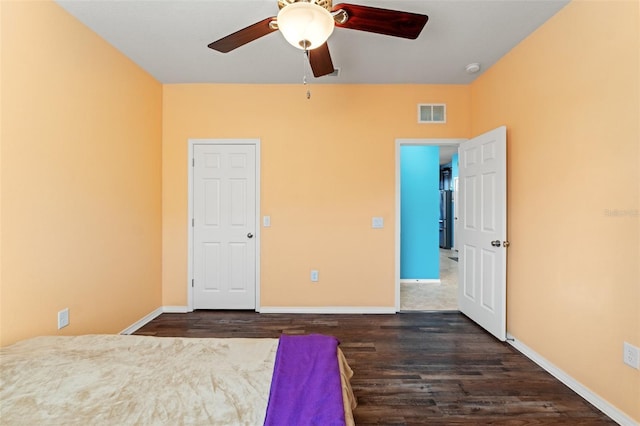 unfurnished bedroom featuring a ceiling fan, visible vents, dark wood finished floors, and baseboards