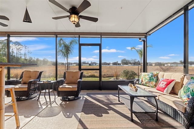 sunroom / solarium with a ceiling fan and a rural view