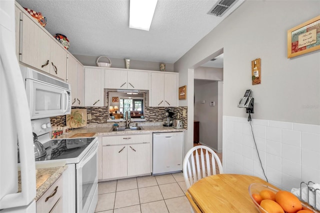 kitchen with sink, white appliances, light tile patterned floors, white cabinetry, and a textured ceiling