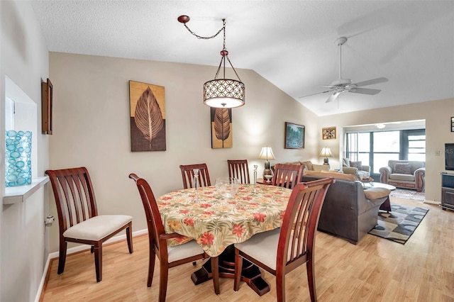 dining space with ceiling fan, light hardwood / wood-style floors, and vaulted ceiling