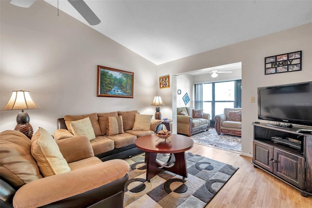 living room with ceiling fan, vaulted ceiling, and light wood-type flooring