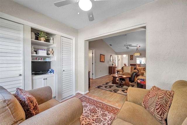 living room with lofted ceiling, light hardwood / wood-style flooring, a textured ceiling, built in features, and ceiling fan