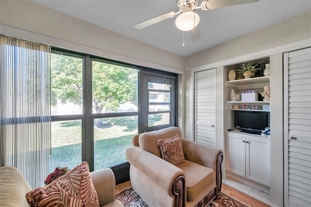 living area featuring light tile patterned floors and ceiling fan