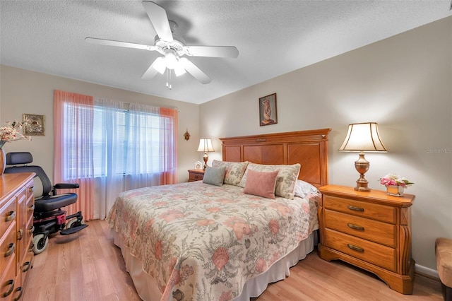 bedroom featuring ceiling fan, light hardwood / wood-style floors, and a textured ceiling