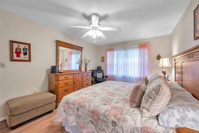 bedroom featuring ceiling fan, a textured ceiling, and light hardwood / wood-style flooring