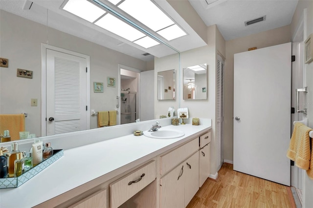 bathroom featuring vanity, hardwood / wood-style floors, and a shower with door