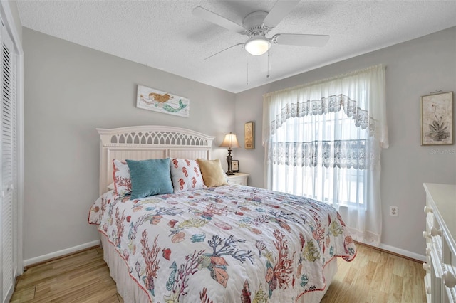 bedroom featuring ceiling fan, a closet, a textured ceiling, and light wood-type flooring