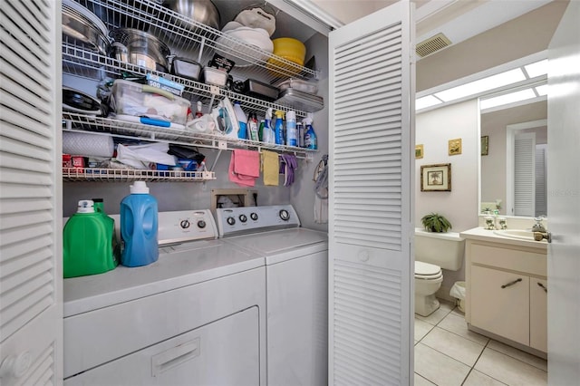 clothes washing area featuring independent washer and dryer, sink, and light tile patterned floors